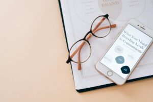 Stylish flat lay of eyeglasses, smartphone, and branding document on a desk.